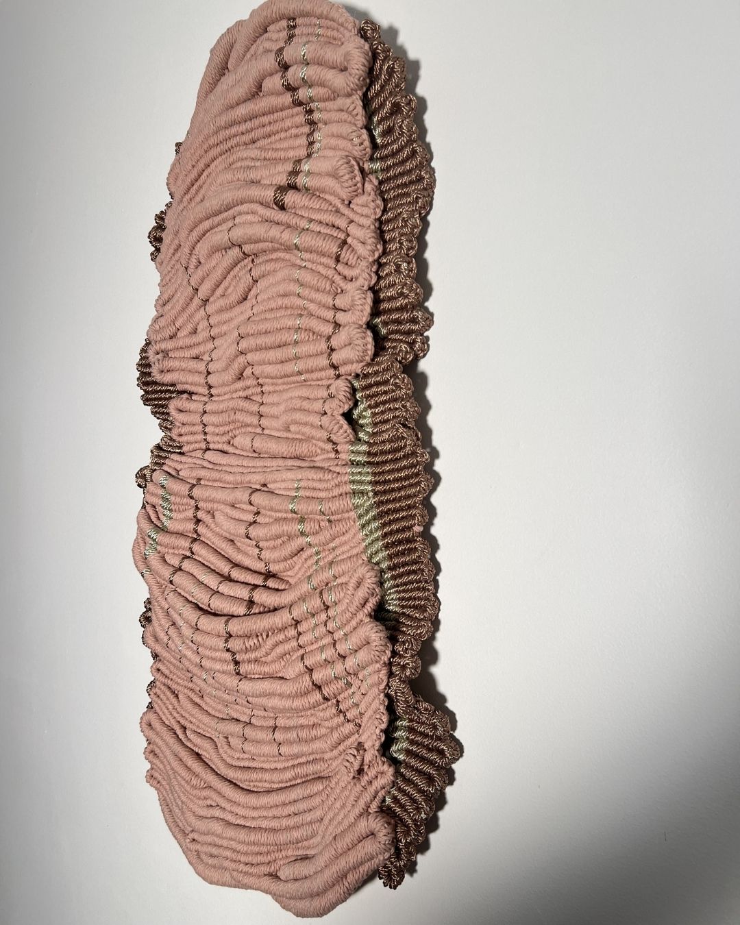 Abstract textile wall hanging with soft pink tones and textured surface