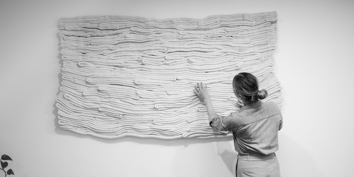Person interacting with a large abstract sculpture on a white wall
