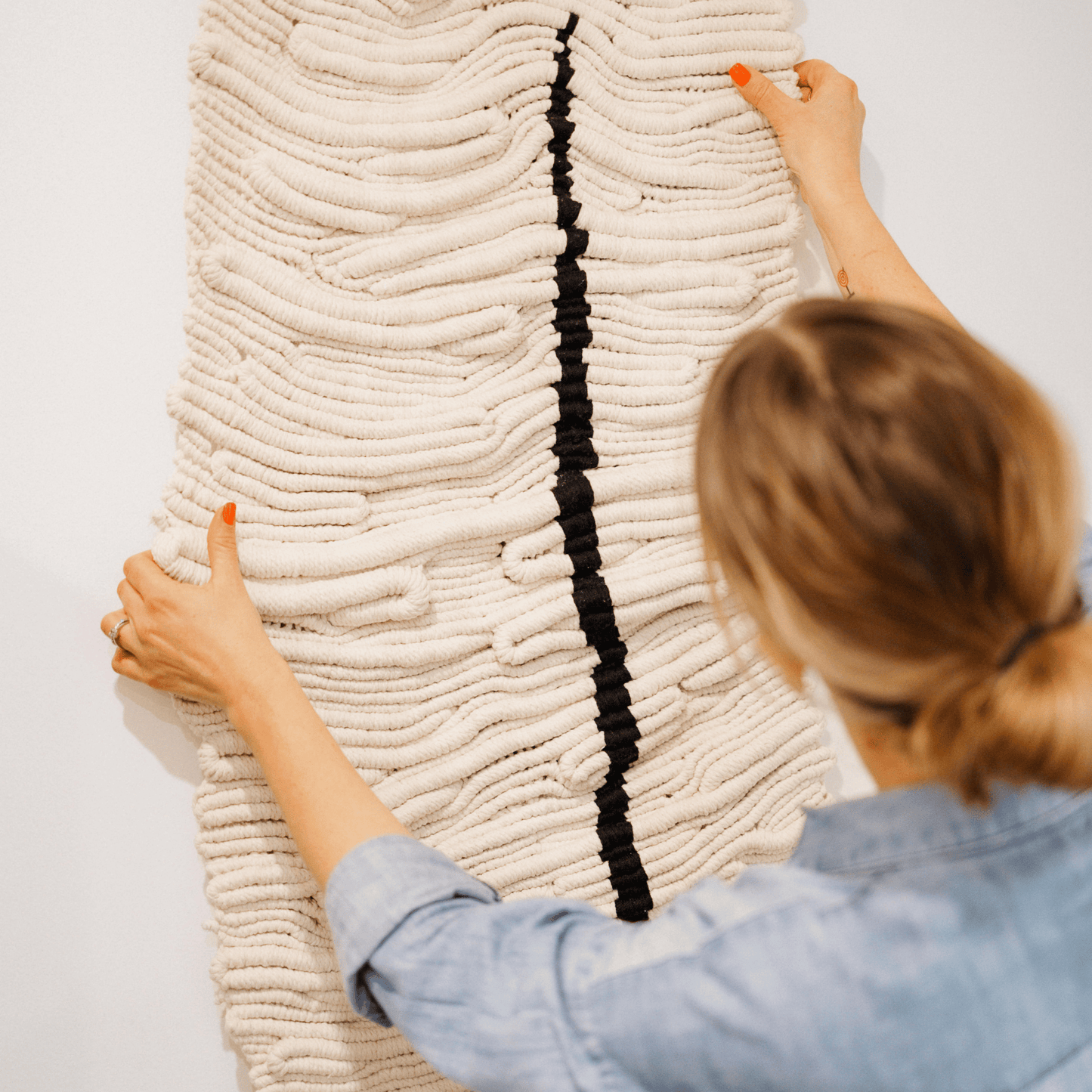 The Scars Within – textured contemporary textile wall art being hung by the artist