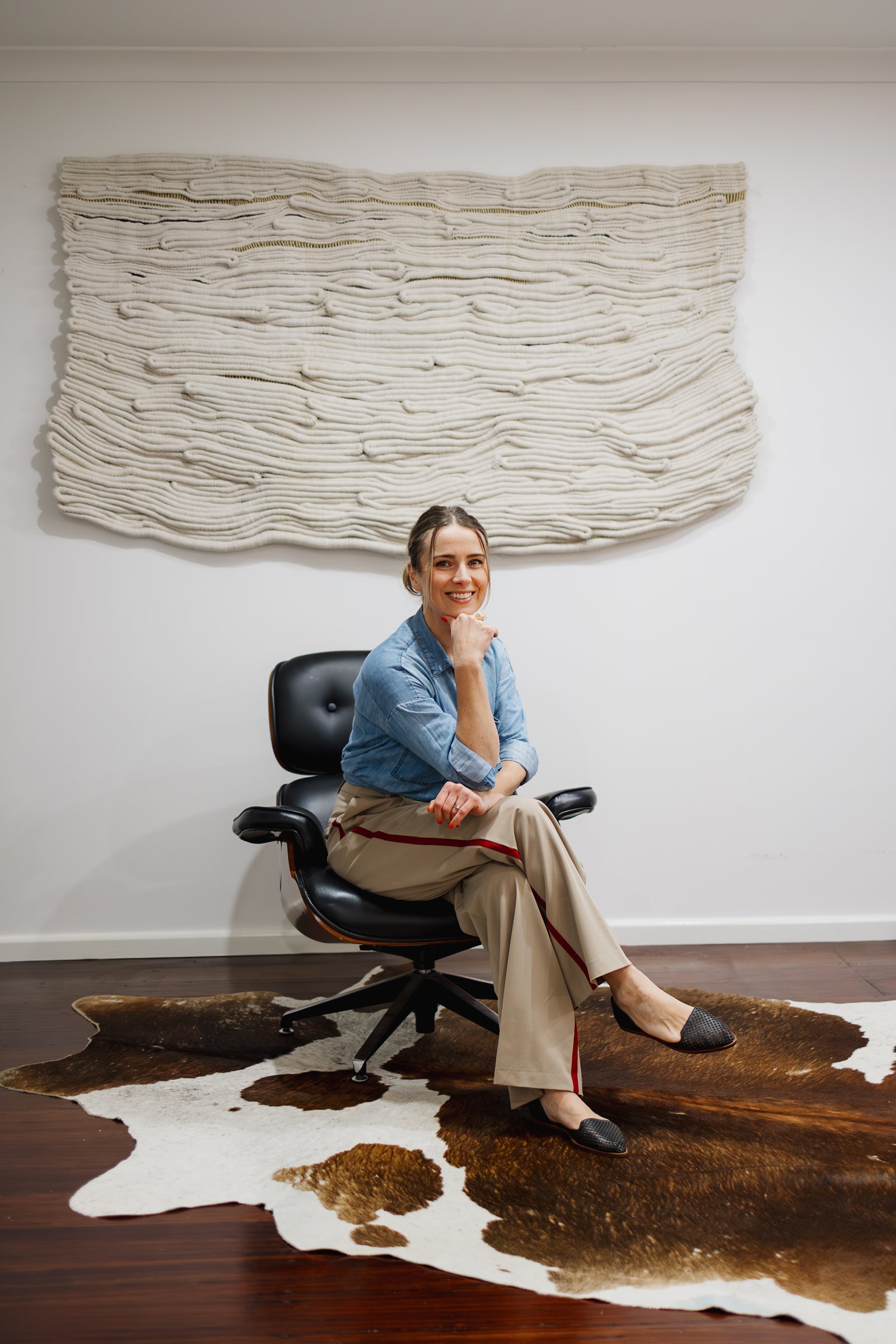 Kasia, the artist knotted by hand sitting in front of her work, a sculptural fibre wall art.
