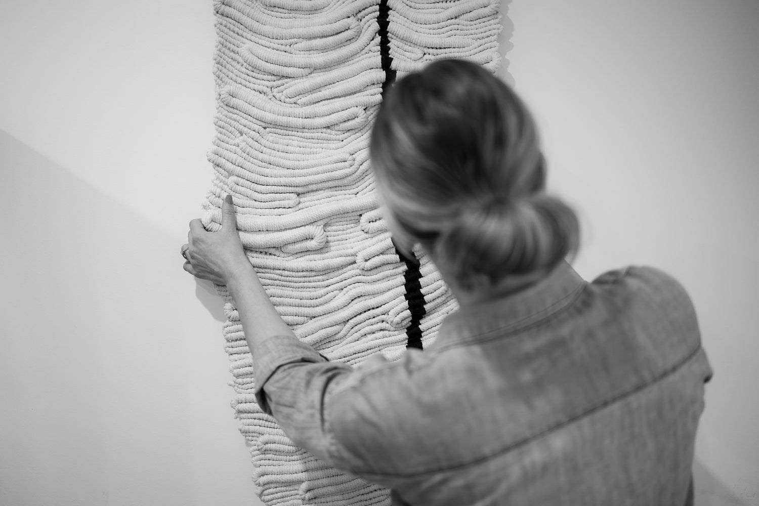 Artist interacting with a textured wall art piece, knotted by hand