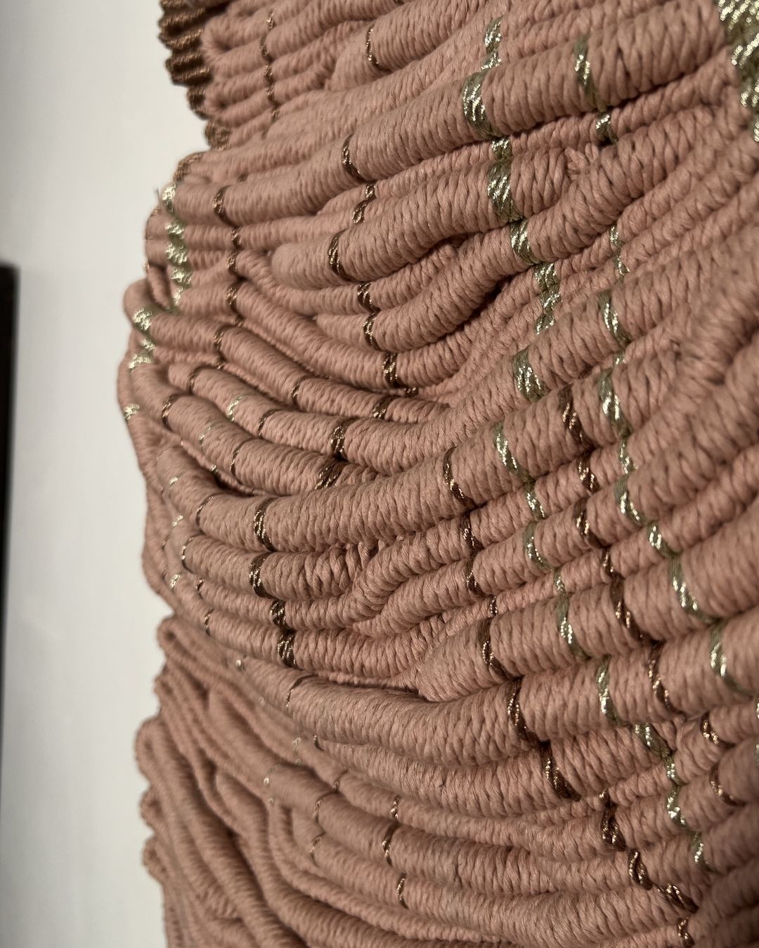 Hand-knotted textile wall art in blush tones with metallic thread detail